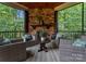 Covered outdoor space featuring a stone fireplace, comfortable seating, and views of the surrounding trees at 3815 Stoney Ridge Trl, Charlotte, NC 28210