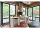 Stylish outdoor kitchen in a sunroom with a stainless steel grill, mini fridge, and natural stone countertops at 405 Gladelynn Way, Waxhaw, NC 28173