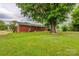 A brick house features a well-manicured lawn and mature trees, creating a serene backyard at 413 N Mulberry St, Cherryville, NC 28021