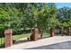Landscaped backyard featuring a brick retaining wall, lighting, and mature trees at 5718 Bardsey Ct, Matthews, NC 28104