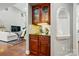Wet bar featuring wooden cabinetry, glass shelving, and decorative niche in open-concept living space at 5718 Bardsey Ct, Matthews, NC 28104