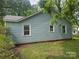 Side exterior view shows light blue vinyl siding and several windows overlooking the backyard at 6407 Market St, Charlotte, NC 28215