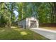 A detached garage with a roll-up door sits on a grassy lot surrounded by mature trees at 7416 Cross Tie Ct, Mint Hill, NC 28227