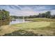 Scenic view of a golf course with a lake, lush green grass, and trees under a partly cloudy sky at 7600 Ridgefield Dr, Charlotte, NC 28269