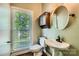 Well-lit powder room with a pedestal sink, decorative mirror, and window with natural light at 7600 Ridgefield Dr, Charlotte, NC 28269