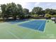 View of the community tennis courts surrounded by mature trees and landscaping at 8017 Prince George Rd, Charlotte, NC 28210