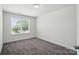 An empty bedroom with gray carpet, white walls, and a window with horizontal blinds at 8018 Saluda Dr, Charlotte, NC 28269