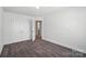 Empty bedroom with gray carpet, white walls, double closet, and a view to a hallway at 8018 Saluda Dr, Charlotte, NC 28269