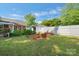 Large backyard with a lush lawn, mature trees, garden beds, a white fence, and a storage shed at 8206 Idlewild Rd # 22, Indian Trail, NC 28079