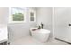 Modern bathroom featuring a free-standing tub, marble style tile, and natural light at 9527 Walkers Ferry Rd, Charlotte, NC 28214