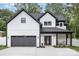 Modern farmhouse exterior featuring black trim, white siding, a two-car garage, and a cozy front porch at 9527 Walkers Ferry Rd, Charlotte, NC 28214