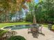 Serene backyard featuring a stone-lined pool, patio with dining set, and lush greenery at 1007 Wessington Manor Ln, Fort Mill, SC 29715