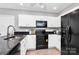 White cabinets and black appliances make for a modern kitchen with black countertops and vinyl flooring at 101 Creekside Dr, Fort Mill, SC 29715