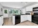 A kitchen with black appliances, white cabinets, a window-lined dining area, and vinyl flooring at 101 Creekside Dr, Fort Mill, SC 29715