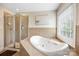 Well lit bathroom features a tiled shower, soaking tub, and window to bring in natural light at 10452 Quiet Bay Ct, Charlotte, NC 28278