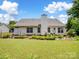 Spacious backyard with lush green grass, garden beds, and a charming white exterior at 11332 Ridge Oak Dr, Charlotte, NC 28273