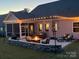Backyard patio at dusk featuring a cozy fire pit, comfortable seating, and string lights, creating a warm ambiance at 1360 Dali Blvd, Mount Holly, NC 28120