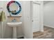 Stylish powder room with pedestal sink, colorful mirror, and modern flooring at 1360 Dali Blvd, Mount Holly, NC 28120