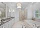 Luxurious bathroom with double vanity, soaking tub, glass-enclosed shower, and elegant lighting at 18823 Peninsula Cove Ln, Cornelius, NC 28031