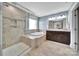 Bright main bathroom featuring a glass shower, soaking tub, granite counters, and and dark wood cabinets at 2015 Knocktree Dr, Indian Trail, NC 28079