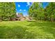 Expansive backyard with lush green grass, mature trees, wooden fence, and a distant home at 229 River Birch Cir, Mooresville, NC 28115