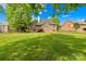 Large backyard with a lush lawn, mature trees, and a charming brick home with a deck at 229 River Birch Cir, Mooresville, NC 28115