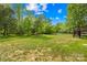 Expansive backyard with lush green grass, mature trees, a wooden fence, and playground set at 229 River Birch Cir, Mooresville, NC 28115