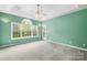Spacious bedroom featuring a tray ceiling, large windows, sconces, and neutral carpet; a perfect primary suite at 229 River Birch Cir, Mooresville, NC 28115