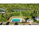 Aerial view of a community pool with a clubhouse surrounded by lush trees and a lake at 245 Rock Ridge Ln, Mount Holly, NC 28120