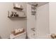 Bright bathroom featuring floating shelves, a toilet with wicker basket, and tiled shower over tub at 2808 Findley Rd, Statesville, NC 28625