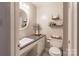 Well-lit bathroom featuring a sink, toilet, decorative shelves, and a round mirror over the sink at 2808 Findley Rd, Statesville, NC 28625