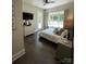 A bright bedroom with wood floors, TV, white dresser, and natural light from the windows and glass door at 3201 Johnny Cake Ln, Charlotte, NC 28226