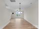 Spacious living room with wood-look floors, a modern light fixture, and bright windows at 3220 Riley Ave, Charlotte, NC 28269