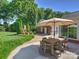 Outdoor dining and entertainment space with brick fireplace, lush greenery, and an attached garage at 3620 Champaign St, Charlotte, NC 28210