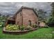 Brick two-story home with a wood balcony overlooking the landscaped yard and decorative retaining wall at 3700 Nw Gainesway Nw Ct, Concord, NC 28027