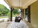 Cozy front porch featuring a hanging wicker chair, stone flooring, and natural wood accents at 4711 Truscott Rd, Charlotte, NC 28226