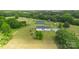 An aerial shot of a white home, green barn, and expansive lush lawn surrounded by mature trees on a sunny day at 4855 Saluda Rd, Rock Hill, SC 29730