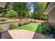 Landscaped backyard featuring a lush lawn, mature plantings, and a paved patio area with built-in BBQ at 54 Honeysuckle Woods, Clover, SC 29710