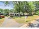 Quaint single-story home on a large lot, surrounded by mature trees and a green lawn at 6517 Paleface Pl, Charlotte, NC 28214