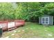 This backyard features a wooden deck and a storage shed, all surrounded by lush greenery at 9021 Louvaine Dr, Charlotte, NC 28227