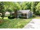 Charming single-story home showcasing a brick chimney, lush landscaping, and inviting curb appeal at 9021 Louvaine Dr, Charlotte, NC 28227
