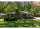 Charming single-story home featuring a brick chimney, a light-blue front door, and lush landscaping at 9021 Louvaine Dr, Charlotte, NC 28227