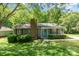 Charming single-story home featuring a brick chimney, a light-blue front door, and lush landscaping at 9021 Louvaine Dr, Charlotte, NC 28227
