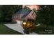 Brick home with a three-car garage, mature landscaping, and a lamppost lit at dusk at 905 Patricians Ln, Monroe, NC 28110
