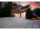 Brick home with a three-car garage and a large driveway at dusk at 905 Patricians Ln, Monroe, NC 28110