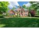 Stately brick home with mature landscaping, green lawn, and black shutters at 905 Patricians Ln, Monroe, NC 28110