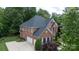 Aerial view of a large brick home with a lush green lawn, mature trees, and an attached three-car garage at 905 Patricians Ln, Monroe, NC 28110