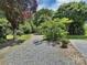 Gravel driveway leading to lush greenery and mature trees, offering privacy at 104 Tobe Bridge Rd, Kings Mountain, NC 28086
