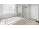 Elegant bathroom featuring a soaking tub, glass-enclosed shower, and tiled walls for a spa-like experience at 10693 Sky Chase Nw Ave, Concord, NC 28027
