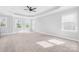 Spacious primary bedroom with carpet flooring, a ceiling fan, and large windows allowing for ample natural light at 10693 Sky Chase Nw Ave, Concord, NC 28027